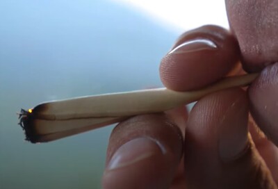 Мужчина с сигаретой в руке делает затяжку